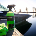 A bottle of Seipel Marine Water Spot Remover on a dock with a green microfiber cloth, with a boat and lake in the background.