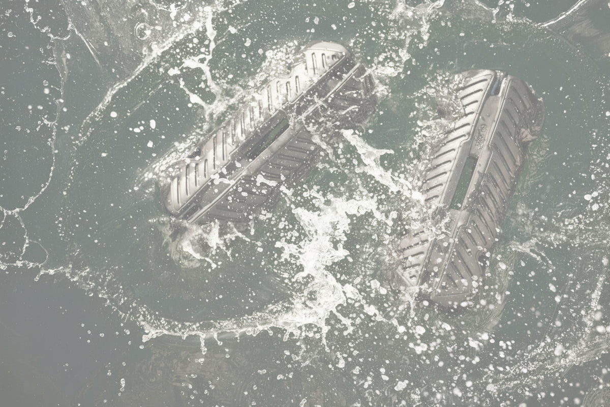 Two black inflatable fenders splashing in the water beside a boat.