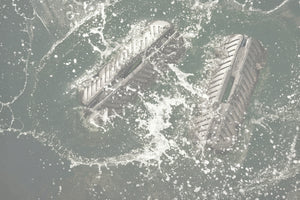 Two black inflatable fenders splashing in the water beside a boat.