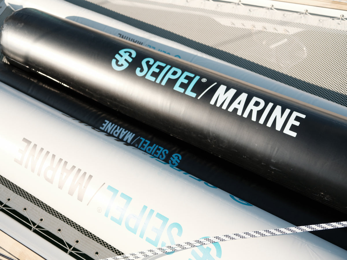 Close-up of black inflatable dock fenders with Seipel Marine logo resting on a boat deck.