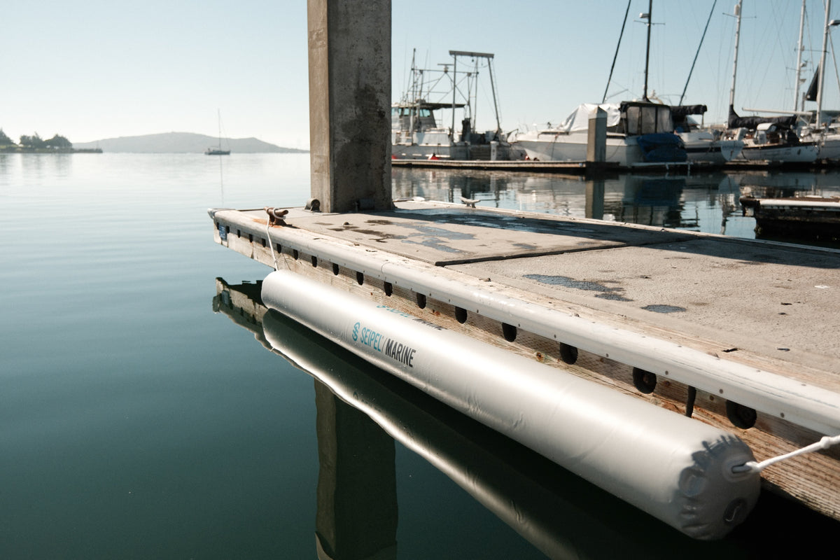 Seipel Marine inflatable dock bumper installed along the side of a dock near calm water.