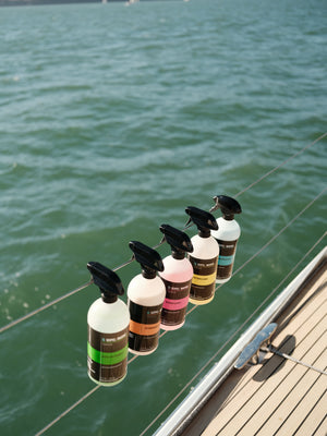 Five Seipel Marine spray bottles hanging from lifelines along a sailboat rail.