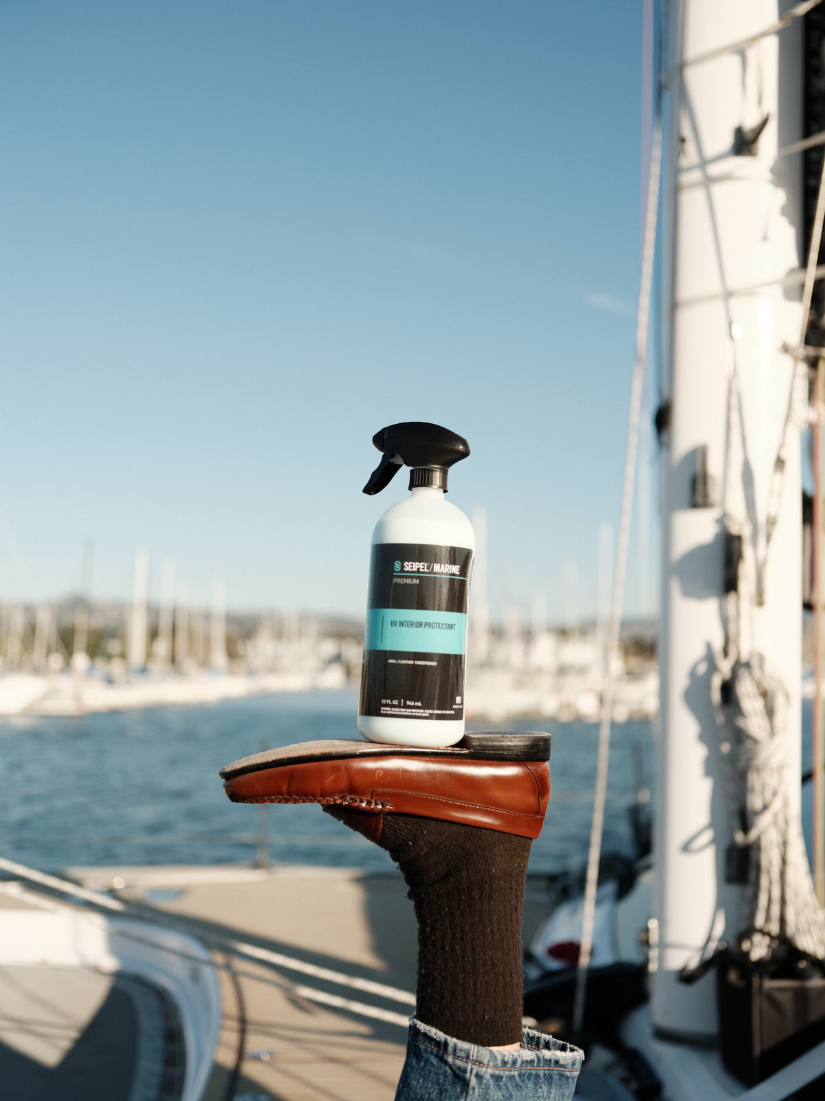 Seipel Marine UV interior protectant spray bottle balanced on a shoe aboard a sailboat at a marina.